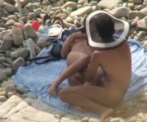 Una pareja de novios amantes en la playa nudista tomando el sol. Estaban totalmente desnudos y no tenían ni idea de que los estaban grabando un voyeur que andaba por ahí. Pillados en la playa..